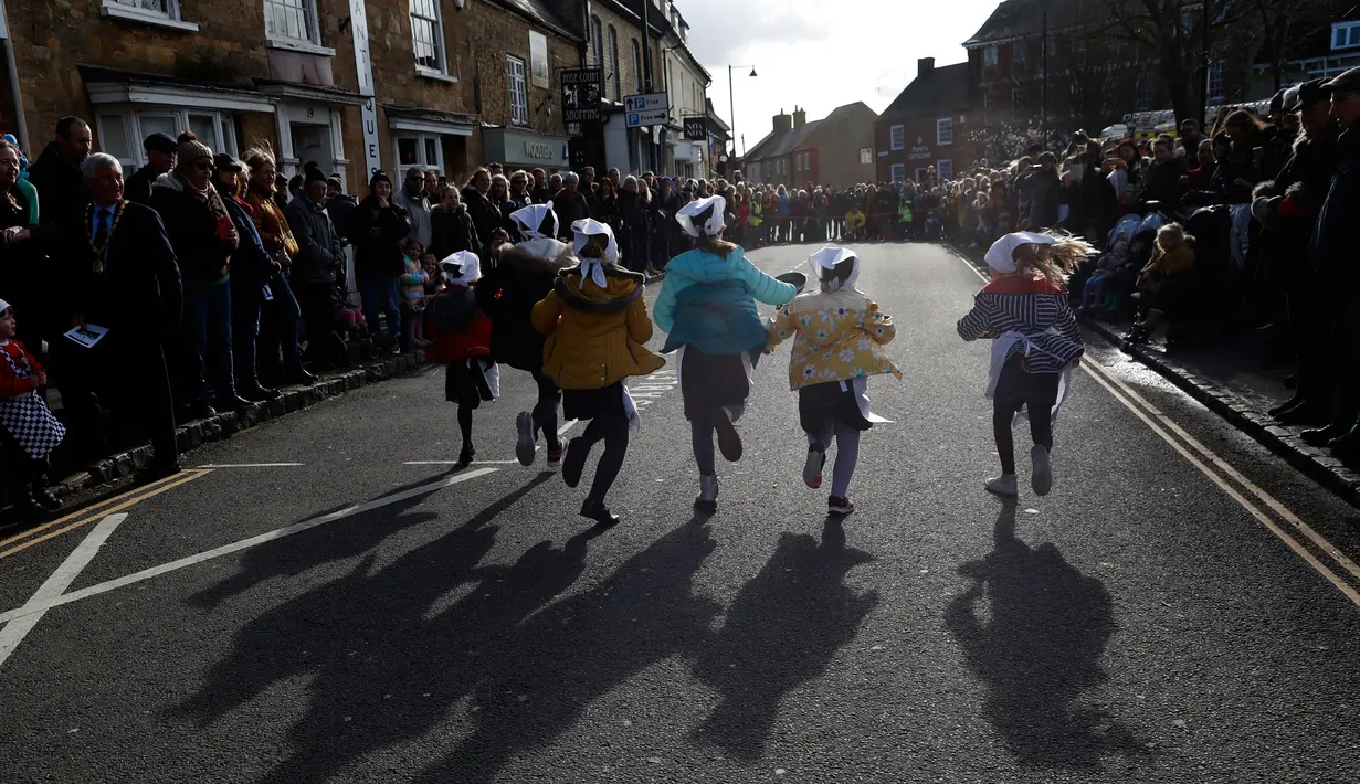 Anak-anak sekolah-sekolah lokal mengambil bagian dalam lomba lari sembari membawa wajan berisi pancake di Olney, Buckinghamshire, Inggris, Selasa (25/2/2020). Peserta kompetisi yang sudah ada sejak tahun 1445 ini harus membolak-balikan pancake sambil tetap berlari. (AP/Alastair Grant)