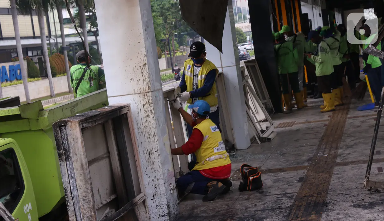 Sejumlah petugas membersihkan sisa kerusakan Halte Bus TransJakarta Tosari, Jakarta, Jumat (9/10/2020). Sejumlah fasilitas umum rusak dalam kericuhan unjuk rasa menolak pengesahan UU Cipta Kerja yang terjadi Kamis (8/10).  (Liputan6.com/Angga Yuniar)
