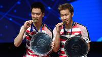 Ganda putra Indonesia, Kevin Sanjaya (kiri) dan Marcus Fernaldi berpose di podium sambil memegang piala usai mengalahkan pebulutangkis Denmark Mathias Boe dan Carsten Mogensen di final All England di Birmingham, Inggris (18/3). (AFP Photo/Paul Ellis)