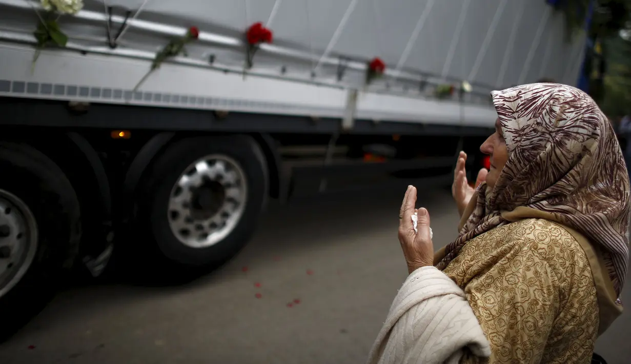 Seorang wanita berdoa di depan truk yang membawa 136 peti mati korban pembantaian Srebrenica, di desa Visoko, Bosnia-Herzegovina, Kamis, (9/7/2015). ini merupakan pembantaian terburuk di Eropa sejak Perang Dunia II. (REUTERS/Stoyan Nenov)