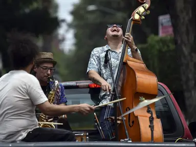 Band Maroto Jazz Trio yang terdiri dari Diego Maroto pada Saxophone, Jorge Molina pada double bass, dan Edy Vega pada drum tampil dari atas sebuah van melewati kawasan Mexico City, Meksiko, 29 Agustus 2020. Penampilan mereka dilakukan di tengah pandemi virus corona COVID-19. (RODRIGO ARANGUA/AFP)
