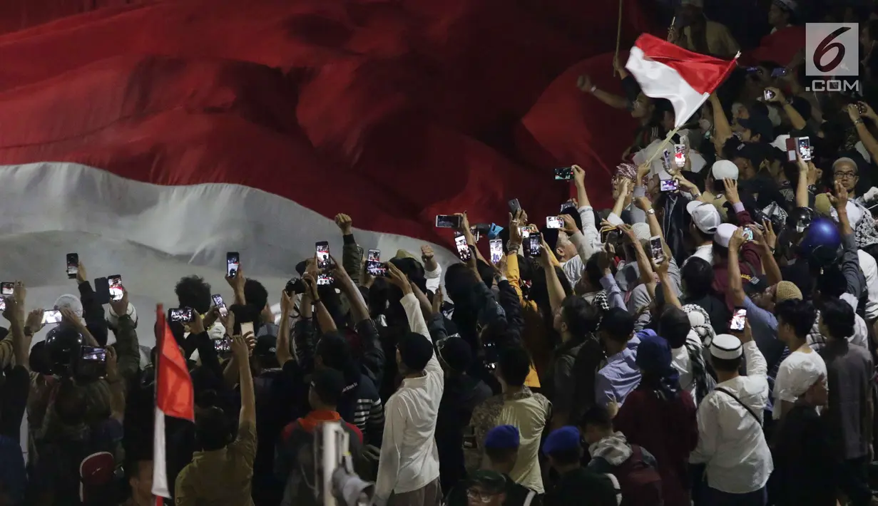 Massa aksi Gerakan Nasional Kedaulatan Rakyat mengibarkan bendera Merah Putih raksasa usai berbuka puasa dan salat maghrib berjemaah di perempatan sekitar Gedung Bawaslu, Jakarta, Rabu (22/5/2019). (Liputan6.com/Helmi Fithriansyah)