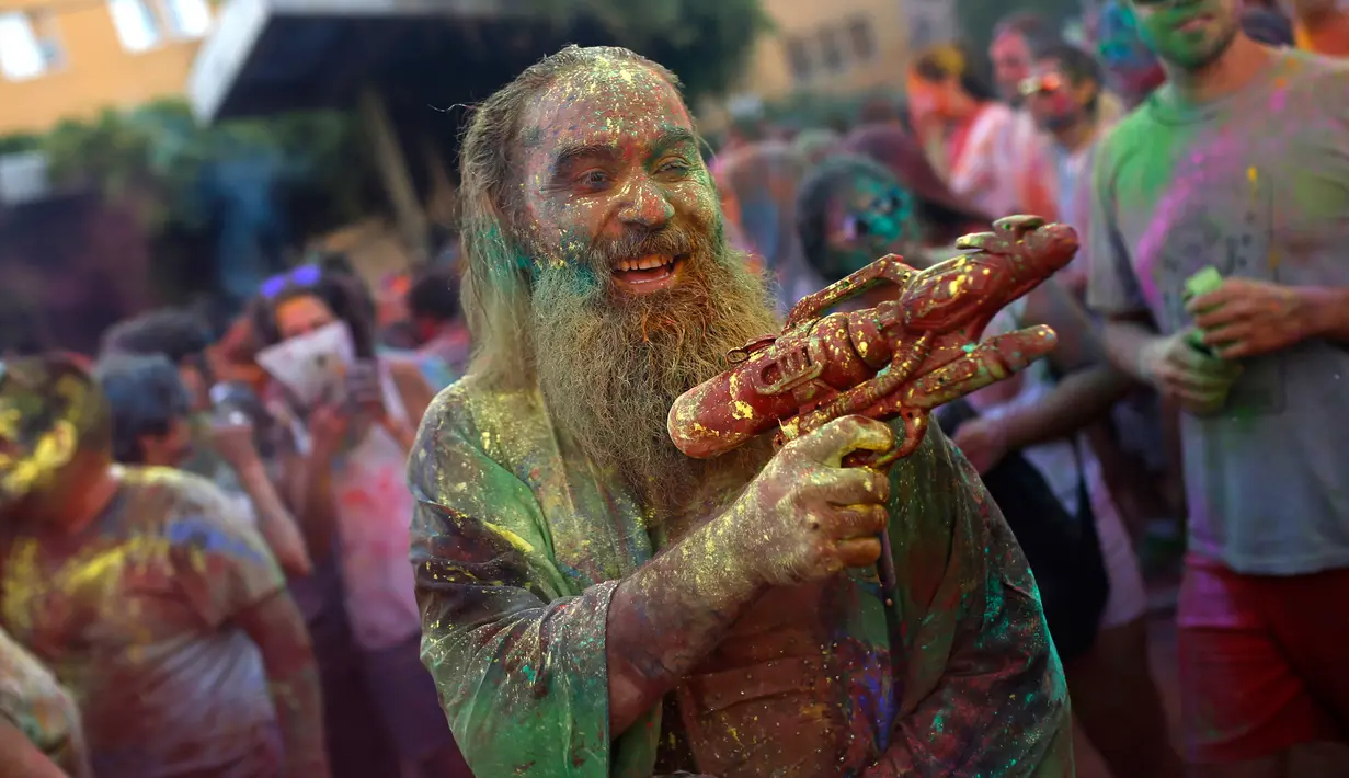 Seorang pria dengan tubuh penuh cat memegang pistol plastik saat mengikuti Festival Monsoon Holi di Madrid, Spanyol (5/8). Festival yang menjadi salah satu tradisi di India dan Nepal ini, kini menjadi trend di sejumlah negara. (AP Photo/Francisco Seco)