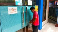 Seorang pria menggembok pintu masuk kantor Camat Bukitraya karena tiga pegawainya positif Covid-19. (Liputan6.com/M Syukur)