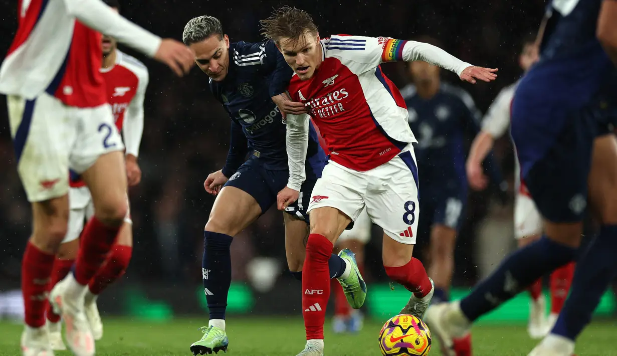 Gelandang Manchester United, Antony (kiri) berebut bola dengan pemain Arsenal Martin Odegaard pada lanjutan Liga Premier Inggris 2024/2025 di Stadion Emirates, London pada Rabu 4 Desember 2024 waktu setempat atau Kamis 5 Desember 2024 dini hari WIB. (Adrian Dennis/AFP)