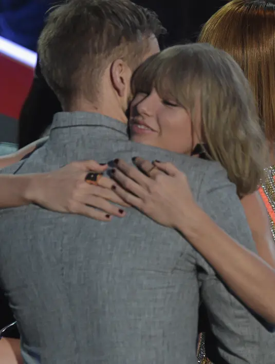 Ketika berada didalam venue iHeart Music Radio, nampaknya Taylor Swift tak menghiraukan gosip implan pada bokongnya. Justru Taylor Swift asik berpelukan dengan Calvin Harris. (AFP/Bintang.com)