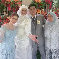 Kakak Tissa Biani, Alita tampil mengenakan gaun pernikahan warna putih. Sementara itu, sang kakak ipar mengenakan setelan jas warna abu-abu dengan bros bunganya. @tissabiani