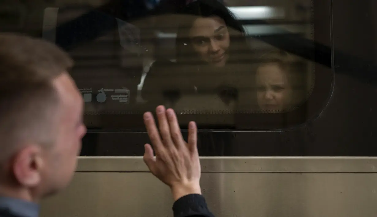Nicolai (41) dari Ukraina mengucapkan selamat tinggal kepada putrinya Elina (4) dan istrinya Lolita dalam kereta menuju Polandia untuk melarikan diri dari perang di stasiun kereta di Lviv, Ukraina, 15 April 2022. Polandia menerima pengungsi Ukraina terbesar. (AP Photo/Emilio Morenatti)