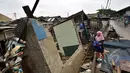 Seorang perempuan melihat kondisi rumah yang rubuh dikawasan muara baru, Jakarta, Jumat (13/2/2015).  Sebanyak 33 rumah di muara baru Jakarta Utara mengalami kemiringan parah dan 2 buah rumah ambruk akibat banjir. (Liputan6.com/Faizal Fanani)