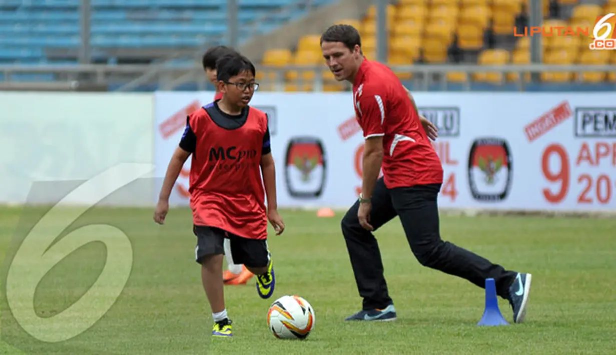 Seorang anak terlihat memainkan bola bersama Michael Owen dalam sesi coaching clinic yang digelar di Stadion GBK Jakarta (Liputan6.com/ Helmi Fithriansyah)