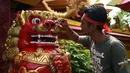 Seorang pekerja mengecat patung di depan kuil Cina di Denpasar, Bali, Senin (23/1). Pengecatan ini dilakukan dalam rangka menyambut pergantian tahun baru Imlek 2568. (AFP PHOTO / SONNY Tumbelaka)