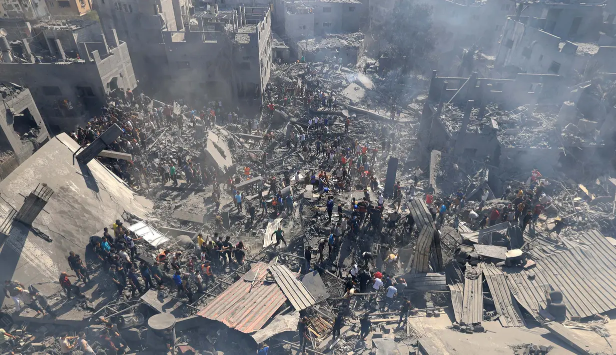 Orang-orang mencari korban di atas reruntuhan bangunan yang hancur usai pengeboman Israel, di Khan Younis di Jalur Gaza Selatan pada 26 Oktober 2023. (Mahmud HAMS/AFP)