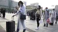 Penumpang yang mengenakan masker dan mantel hujan untuk berkumpul di luar Stasiun Hankou, Wuhan, Provinsi Hubei, China, Rabu (8/4/2020). Setelah 11 minggu lockdown, layanan kereta di kota yang menjadi titik awal pandemi virus corona COVID-19 ini kembali beroperasi. (AP Photo/Ng Han Guan)