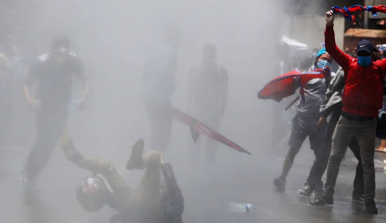 Polisi menembakkan meriam air dan gas air mata untuk membubarkan massa di Nepal (11/6/2020). Sekitar 1000 pemrotes berkumpul menuntut peningkatan pengujian dan dugaan korupsi oleh pejabat pemerintah saat membeli peralatan dan alat uji. (AP Photo/Niranjan Shrestha)