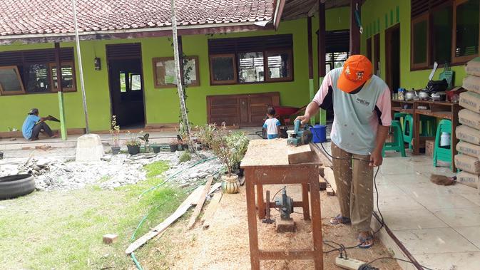 Seorang pekerja tengah membuat kusen sekat kelas Madrasah Diniyah I Cingebul, Lumbir, Banyumas yang sudah rusak dan lapuk. (Foto: Liputan6.com/Muhamad Ridlo)
