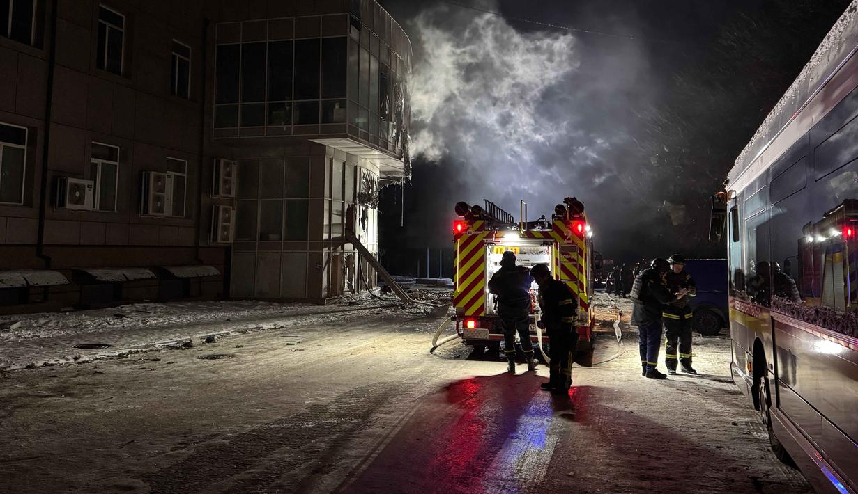 Ini menjadi serangan Rusia pertama di tahun 2026. Tampak dalam foto, petugas pemadam kebakaran berdiri di dekat bangunan tempat tinggal yang rusak akibat serangan pesawat tak berawak Rusia di Zaporizhzhia pada 2 Januari 2026, di tengah invasi Rusia ke Ukraina. (Darya NAZAROVA/AFP)
