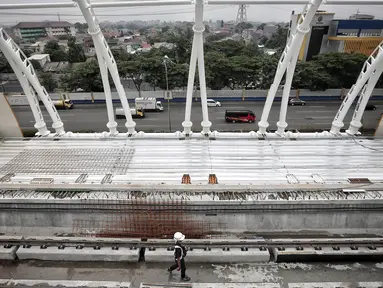 Petugas keamanan melintas di proyek pembangunan Light Rail Transit (LRT) Jabodebek di Stasiun LRT TMII, Jakarta, Senin (14/1). Progres pembangunan Stasiun LRT TMII sudah mencapai 40%. (Liputan6.com/Faizal Fanani)