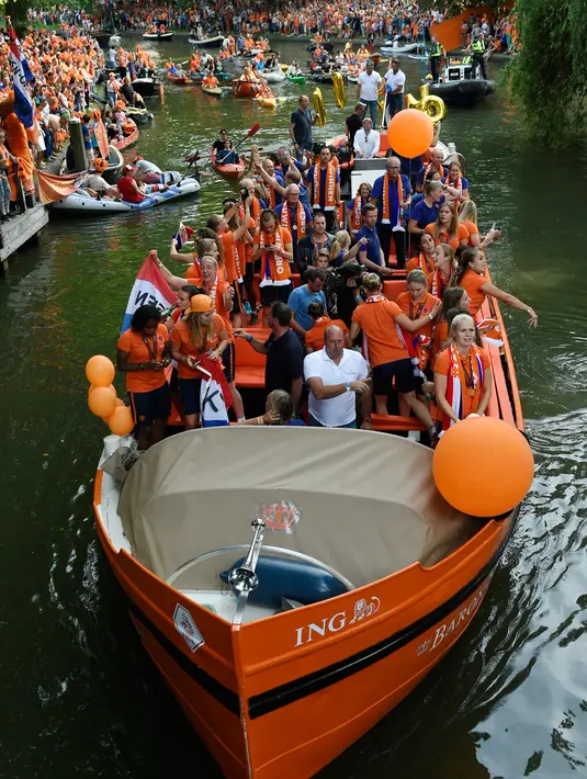Tim sepak bola wanita Belanda menyapa para pendukung dari atas perahu saat merayakan kemenangannya di Utrecht, Belanda (7/9). (AFP Photo/John Thys)