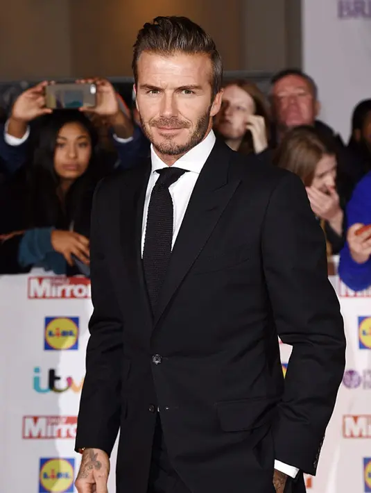 Berpose dengan satu tangan di sakunya, David Beckham berhasil menonjolkan sepasang jas dan celana hitamnya dengan baik, tak lupa dengan dasi hitam yang serasi di dadanya. (via dailymail.co.uk)