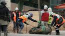 Tim penjinak bom menurunkan bom era Perang Dunia II setelah berhasil dinonaktifkan di distrik padat Wan Chai, Hong Kong, Kamis (1/2). Bom tersebut ditemukan tertanam di tanah yang akan digali untuk konstruksi bangunan. (AP/Vincent Yu)