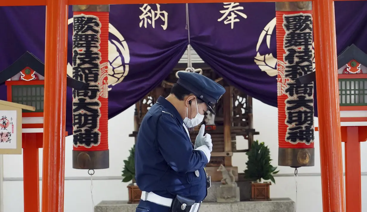 Seorang petugas keamanan yang mengenakan masker pelindung untuk membantu mengekang penyebaran virus corona COVID-19 berjalan di depan sebuah kuil di Tokyo, Jepang, Kamis (15/4/2021). Tokyo mengonfirmasi lebih dari 700 kasus baru COVID-19 pada 15 April 2021. (AP Photo/Eugene Hoshiko)