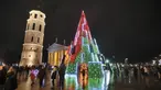 Pohon Natal yang menyala terlihat di dekat katedral di Vilnius, Lithuania pada 28 November 2020. Pohon natal raksasa yang dihiasi berbagai ornamen lampu hias tersebut membuat kawasan di ibu kota Lithuania menjadi terang. (PETRAS MALUKAS / AFP)