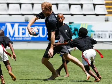Pangeran Harry  bermain rugby dengan anak - anak di Durban , Afrika Selatan, Selasa (1/12). Pangeran Harry di Afrika Selatan untuk mengadakan acara amal yang didirikannya bersama Pangeran Lerotholi Seeiso. (REUTERS/Rogan Ward) 