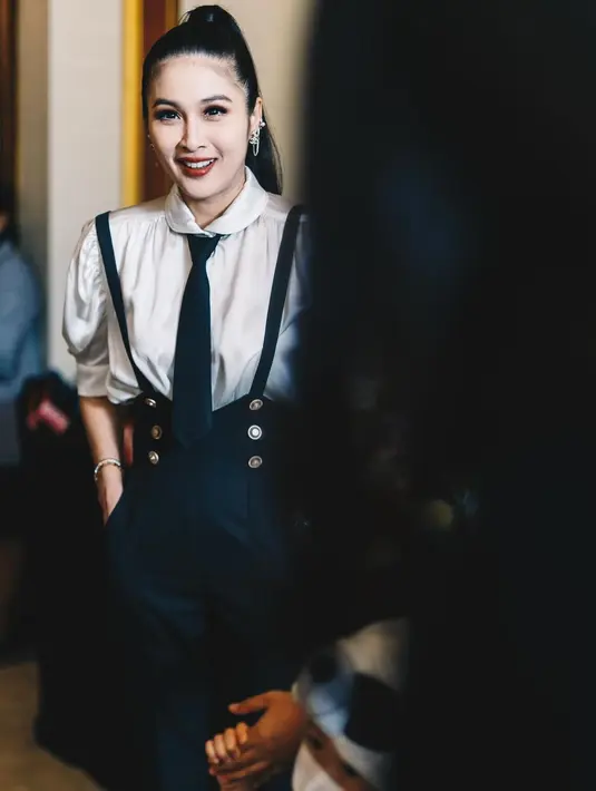 Penampilannya dilengkapi dengan pulasan makeup flawless. Aplikasi lipstik warna merah gelap menambah kesan elegan pada penampilannya. [@sandradewi88]