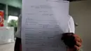 Calon penumpang pesawat AirAsia, Hartono Gunawan menunjukan tiket perubahan jadwal penerbangan Surabaya-Singapura di Terminal 2 Bandara Juanda, Surabaya, Sabtu (3/1/2015). (Liputan6.com/Johan Tallo)