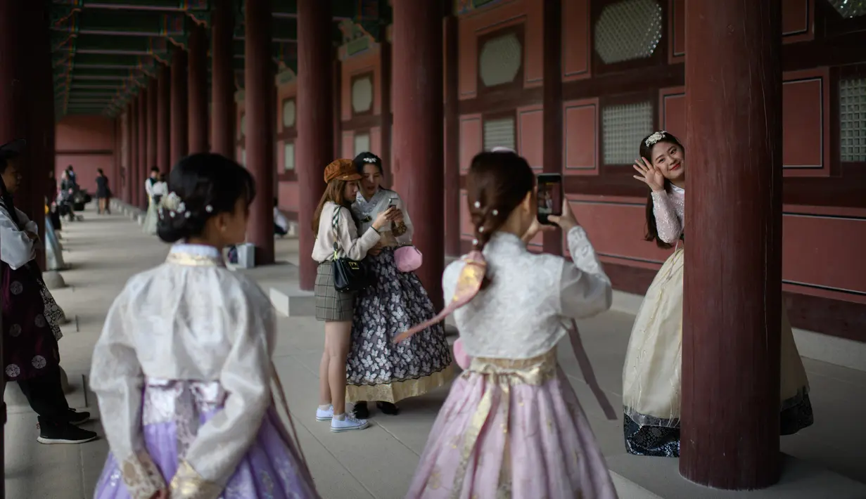 Pengunjung mengenakan pakaian tradisional Korea, Hanbok sambil berpose di istana Gyeongbokgung, Seoul, Rabu (26/9). Korea Selatan sedang menikmati hari terakhir dari liburan Chuseok atau Hari Thanksgiving. (AFP PHOTO / Ed JONES)