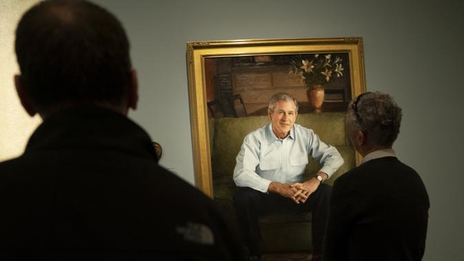 Pengunjung mengamati potret mantan presiden Amerika Serikat George W. Bush dalam pameran bertajuk 