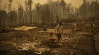 Yeremy Escanilla bekerja membersihkan puing-puing sisa-sisa rumahnya yang hancur akibat kebakaran hutan di Santa Juana, Chile, Minggu (5/2/2023). Gelombang panas musim panas yang terik mempersulit upaya untuk mengendalikan kebakaran. (AP Photo/Matias Delacroix)