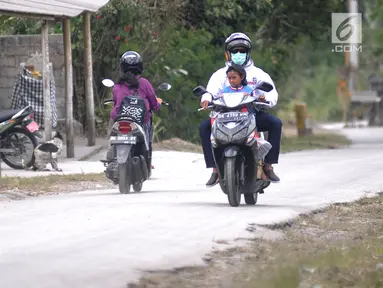 Pengendara sepeda motor mengenakan masker saat melintas di Desa Pempatan, Karangasem, Bali, Sabtu (30/6). Pascaerupsi Gunung Agung, abu vulkanik masih menyelimuti kawasan tersebut. (Merdeka.com/Arie Basuki)