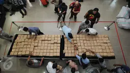 Petugas Dir IV Narkoba Mabes Polri membongkar dan merapikan puluhan pak ganja saat rilis di Jakarta, Selasa (24/5/2016). Petugas menahan enam orang tersangka dengan barang bukti narkoba jenis ganja seberat satu ton. (Liputan6.com/Helmi Fithriansyah)