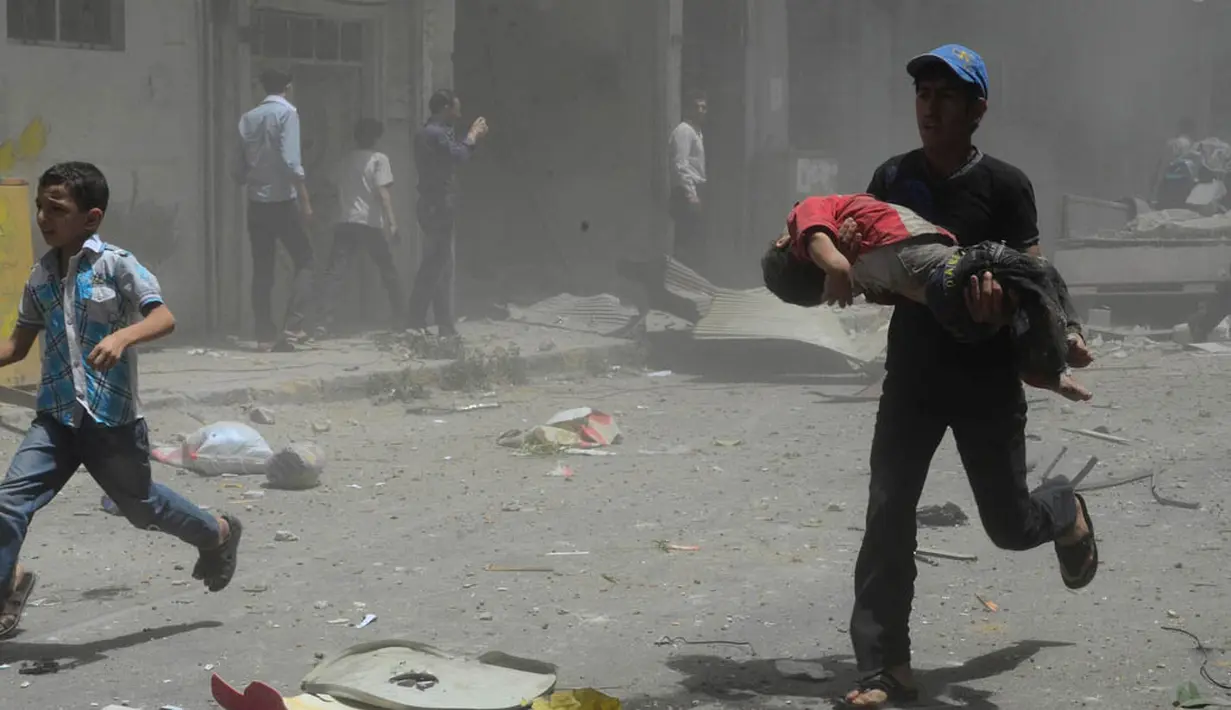 Tampak seorang pemuda berusaha menyelamatkan anak kecil yang terluka   akibat ledakan bom mobil (REUTERS/Yousef Albostany).