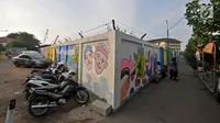 Aktivitas warga di dekat mural Betawi yang berada di Kampung Pitung, Marunda, Jakarta, Senin (2/7). Mural-mural bernuansa Betawi kini menghiasi destinasi wisata rumah dan masjid Pitung. (Merdeka.com/Iqbal S. Nugroho)
