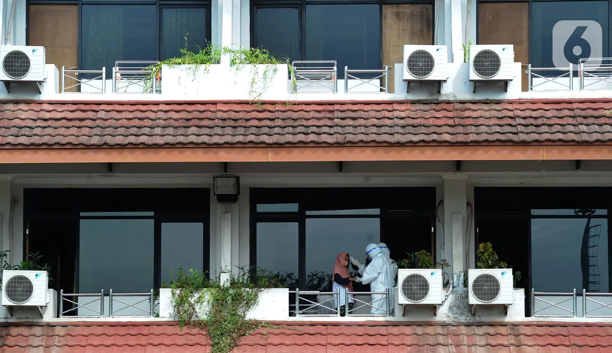 Petugas medis memeriksa suhu tubuh pasien OTG Covid-19 di Graha Wisata Ragunan, Jakarta, (21/12/2020). Pasien positif Covid-19 tanpa gejala atau bergejala ringan hanya perlu isolasi mandiri selama 10 hari. (merdeka.com/Arie Basuki)
