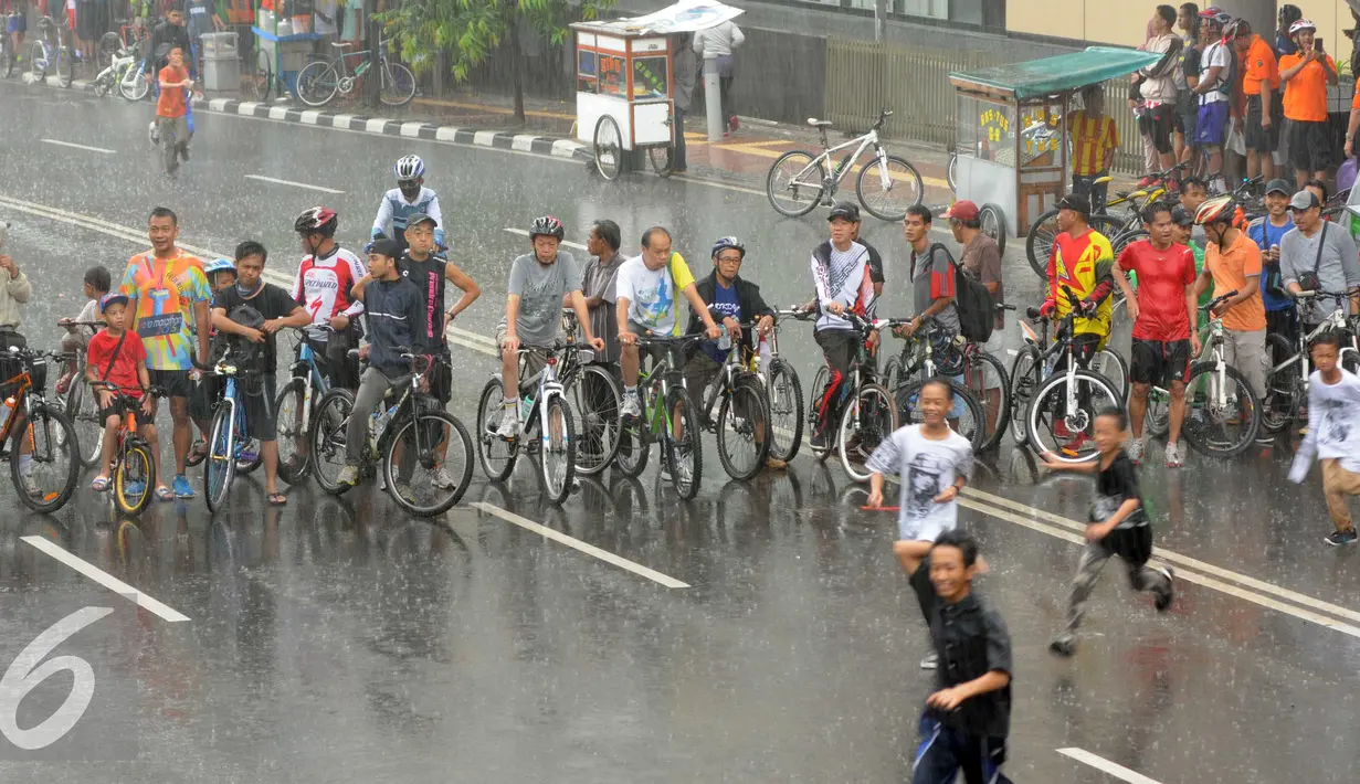 Hujan mengguyur kawasan Bundaran HI saat kegiatan Car Free Day di Jakarta, Minggu (24/1/2016). Sejumlah pengunjung tetap melaksanakan olahraga di bawah guyuran hujan. (Liputan6.com/Helmi Affandi)