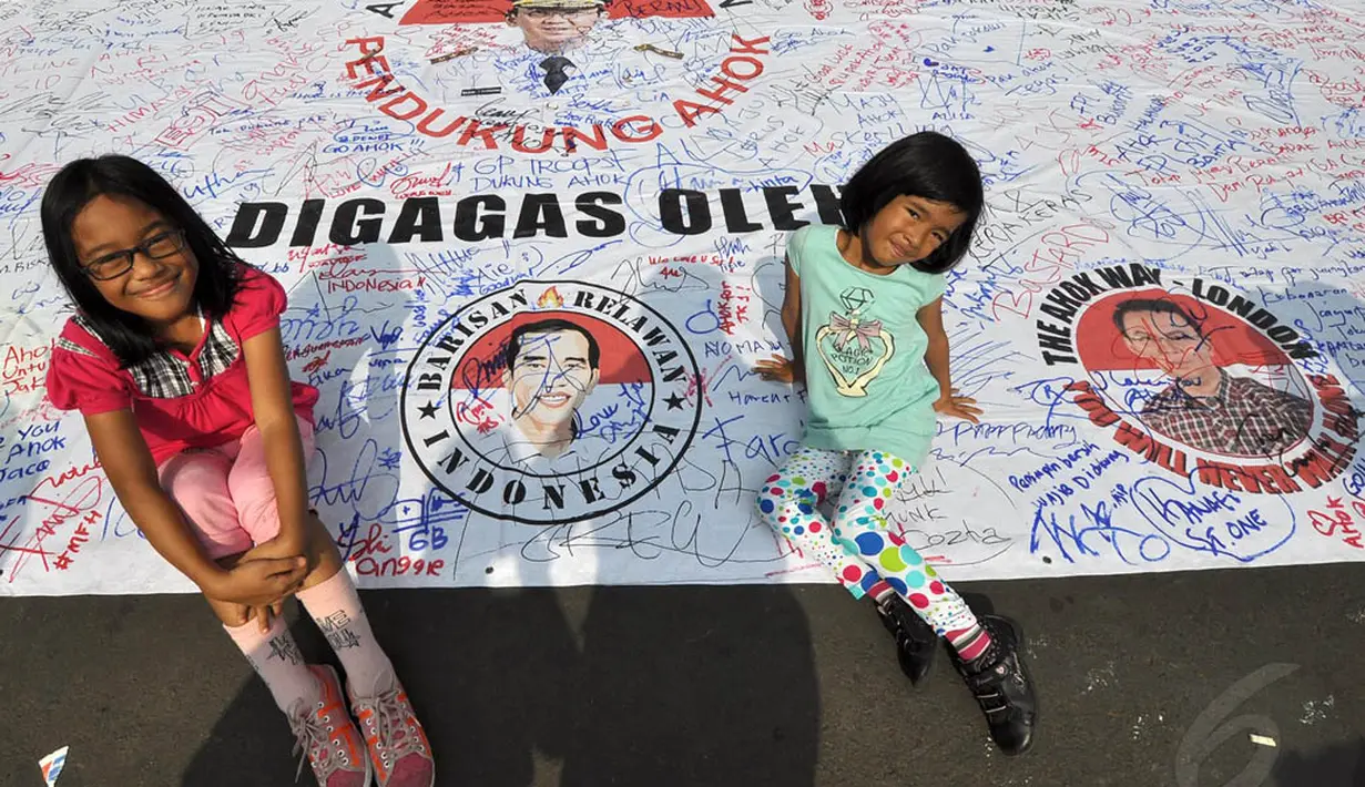 Dua orang anak saat berpose di atas spanduk yang berisi ribuan tanda tangan sebagai bentuk dukungan kepada Ahok, Jakarta. Foto diambil pada 9 November 2014. (Liputan6.com/Miftahul Hayat)