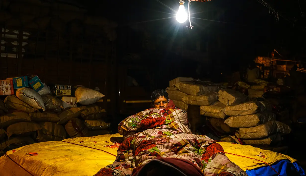Seorang pria tertidur di dekat tumpukan barang di kawasan tua New Delhi, India (6/3). Akan tetapi, predikat itu dicopot karena masalah krisis uang tunai yang terjadi di negara tersebut. (AFP Photo/Chandan Khanna)