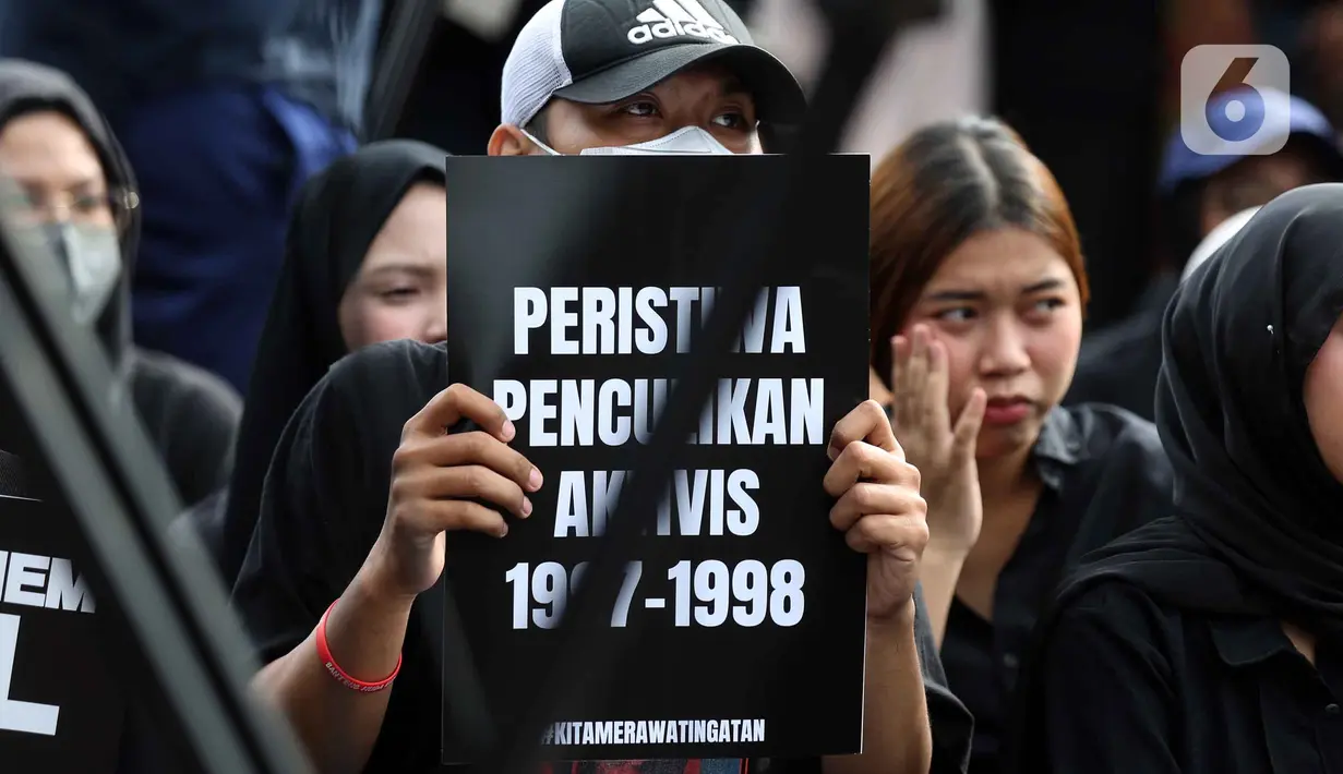 Aksi damai ini kali pertama dilakukan pada 18 Januari 2007. Tampak dalam foto, aktivis Jaringan Solidaritas Korban untuk Keadilan memegang pamflet saat mengikuti peringatan 19 tahun Aksi Kamisan di Jalan Medan Merdeka Utara atau di seberang Istana Merdeka, Jakarta, 15 Januari 2026. (Liputan6.com/Helmi Fithriansyah)