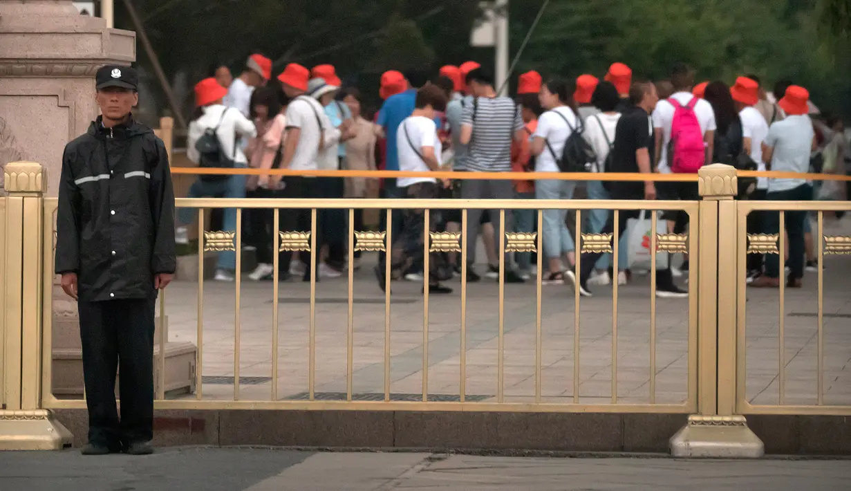 Seorang petugas eamanan berjaga-jaga ketika para wisatawan berjalan di sepanjang jalan di sebelah Lapangan Tiananmen di Beijing (4/6/2019). Pemerintah China meningkatkan keamanan di sekitar Lapangan Tiananmen di pusat Beijing jelang peringatan tragedi Tiananmen 1989. (AP Photo/Mark Schiefelbein)