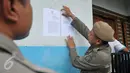 Satpol PP menempelkan surat peringatan kedua (SP2) di salah satu rumah warga di Kalijodo, Jakarta, Kamis (25/2). Dalam SP2 tersebut, warga Kalijodo diberi waktu 3×24 jam untuk mengosongkan/membongkar sendiri bangunan mereka. (Lputan6.com/Gempur M Surya)