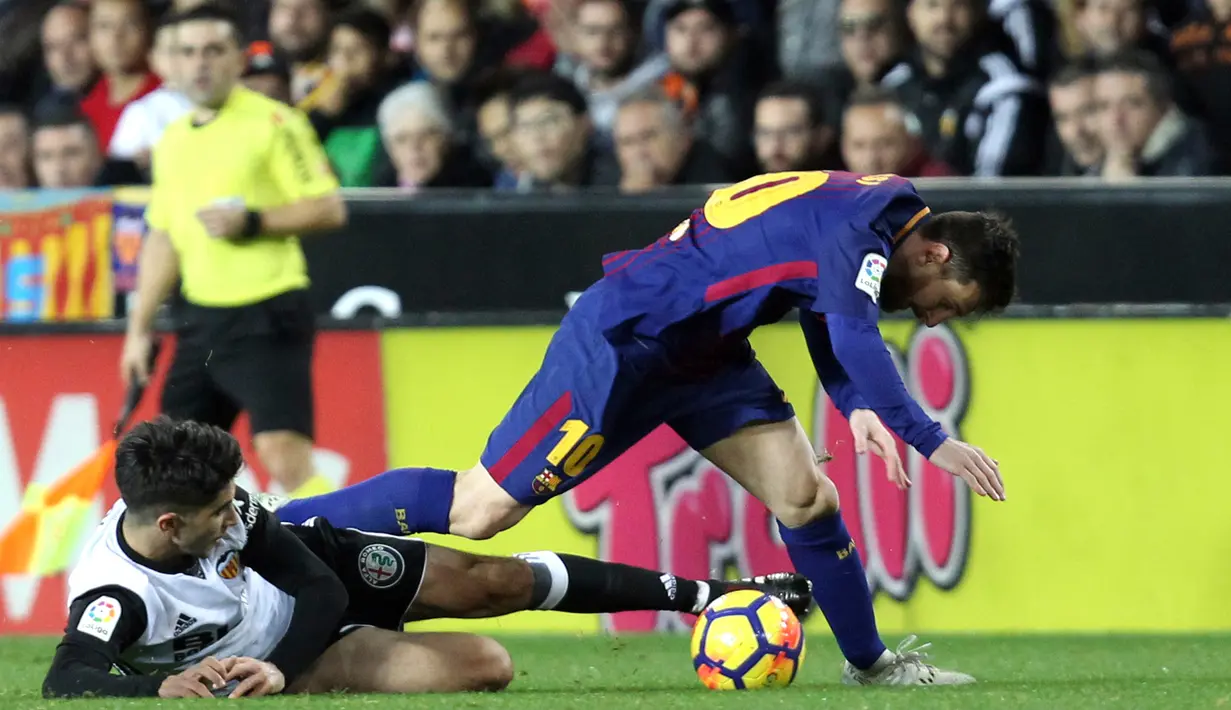 Pemain Barcelona, Lionel Messi berebut bola dengan pemain Valencia, Carlos Soler pada lanjutan La Liga Primera Division di Stadion Mestalla, Minggu (26/11). Valencia memaksa Barcelona meraih hasil imbang 1-1.  (AP/Alberto Saiz)