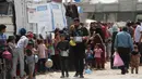 Keluarga-keluarga Palestina yang mengungsi sambil memegang wadah kosong menunggu giliran untuk mengambil makanan dari dapur amal, di kamp pengungsi Bureij, Jalur Gaza Tengah pada Senin 18 Mei 2026. (Eyad Baba/AFP)