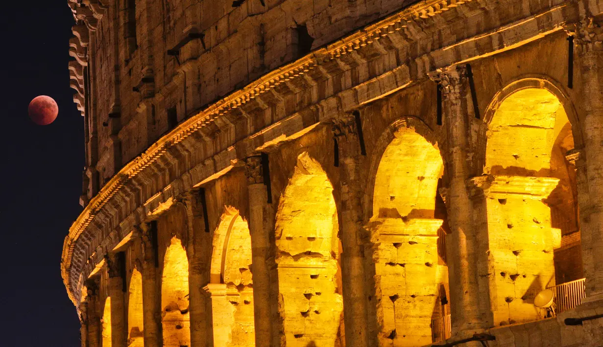 Fenomena gerhana bulan total "Micro Blood Moon" terlihat di dekat Colosseum di Roma, Italia, Jumat (27/7). Gerhana bulan yang terlama pada abad ini dapat disaksikan di seluruh dunia dengan mata telanjang. (AP/Gregorio Borgia)