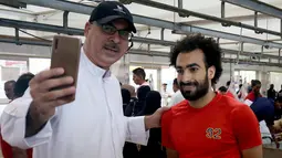 Seorang lelaki Kuwait berselfie dengan tukang daging Mesir Mohammad Ibraheem yang mirip dengan pemain Liverpool Mohamed Salah  di sebuah rumah jagal hewan di Kota Kuwait (13/8/2019). (AFP Photo/Yasser Al-Zayyat)