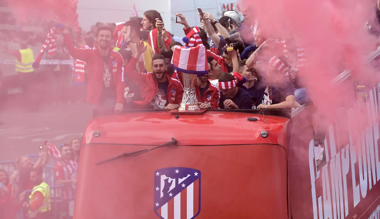 Para pemain Atletico Madrid menyapa suporter saat mengikuti konvoi perayaan gelar Liga Europa di Madrid, Jumat (18/5/2018). Kota Madrid menjadi merah saat perayaan gelar juara Atletico. (AFP/Oscar Del Pozo)