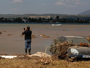 Penduduk lokal Christos Pavlou mengambil gambar mobilnya yang tenggelam setelah badai di desa Bourtzi di pulau Evia, Yunani, Senin (10/8/2020). Tujuh orang, termasuk dua lansia dan bayi berusia delapan bulan, tewas saat badai melanda pulau Evia pada Minggu kemarin. (AP Photo/Thanassis Stavrakis)