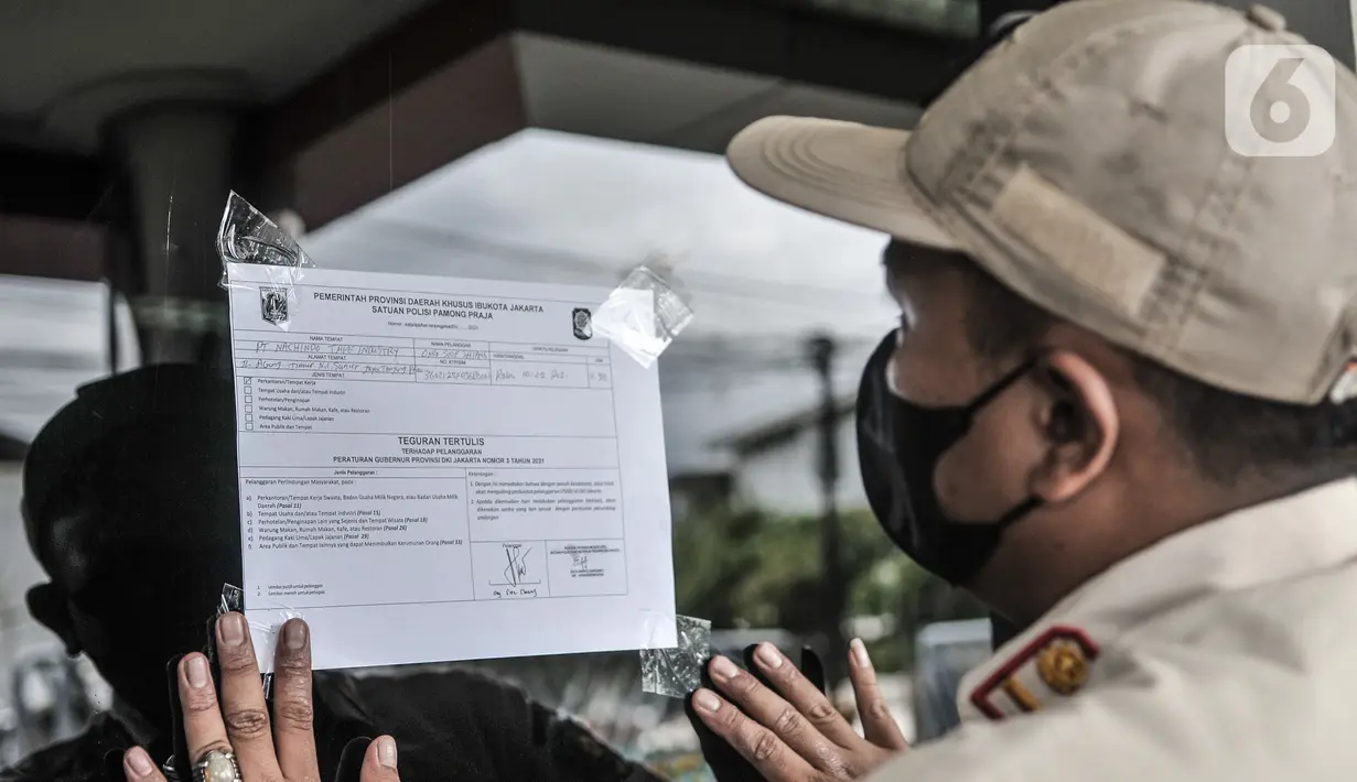 Petugas Satpol PP Kecamatan Tanjung Priok menempelkan surat teguran tertulis saat protokol kesehatan di salah satu perkantoran kawasan Sunter, Jakarta, Rabu (10/2/2021). Sidak digelar dalam rangka meninjau protokol kesehatan di lingkungan perkantoran dan industri. (merdeka.com/Iqbal s Nugroho)
